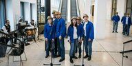 Menschen mit Bauhelmen und blauen Arbeitsjacken im Humboldt Forum, sie scheinen zu singen