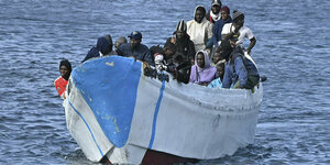 Ein Boot ist voll beladen mit Menschen und schippert auf dem Meer