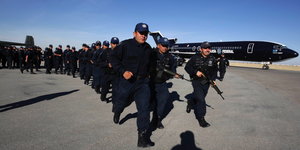 Mexikanische Polizisten rennen über einen Flughafen