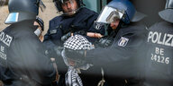 Eine Frau mit Palästinensertuch wird von 3 Berliner Polizisten abgeführt, ein Polizist hält ihr die Augen zu