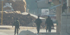 Soldaten sind von hinten auf einer staubigen Straße zu sehen