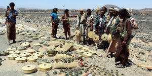 Jemenitische Kämpfer stehen neben einer Minensammlung