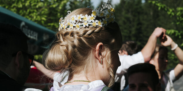 Eine junge Frau in Tracht mit einem Blumenkranz aus Narzissen im Haar