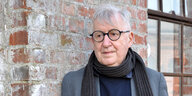 Der Autor Jochen Schimmang vor einer Wand mit schwarem Schal