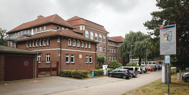 Ein rotes Gebäude, davor ein Parkplatz mit Autos