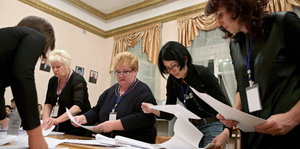 Fünf Frauen zählen Stimmzettel auf einem Tisch