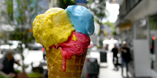 Ein Eis mit drei Kugeln: gelb, rot und blau