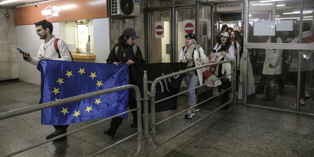 Menschen ziehen durch einen U-Bahnhof, sie tragen eine EU-Fahne