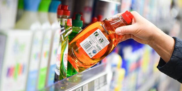 Eine Kundin greift in einem Edeka-Supermarkt nach einer Flasche Spülmittel.
