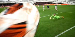 Nahaufnahme des Balls, der zum 3:0 im Tor einschläft. Im Hintergrund die Spieler auf dem Rasen