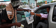 Ein Strassenverkäufer verkauft einem Autofahrer eine Zeitung mit einem Bild des wiedergewählten Präsident Luis Abinader