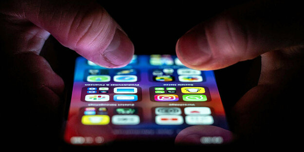 Eine Person bedient ein iPhone auf dem zahlreiche Applikation Apps installiert sind.