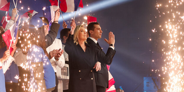 Marine Le Pen und Jordan Bardella bei einer Wahlkampfveranstaltung mit Fahnen und Feuerwerk
