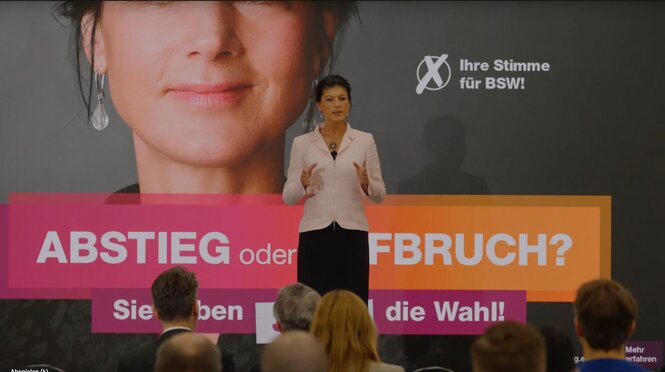 Sahra Wagenknecht steht vor einem Plakat.