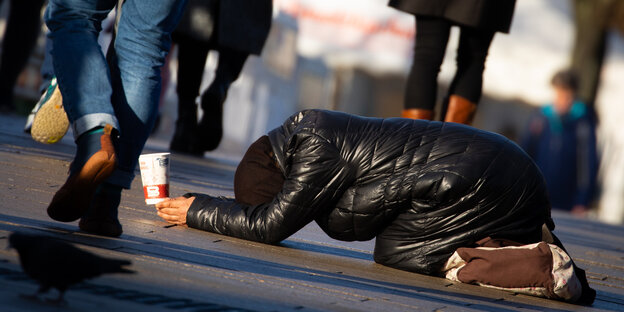Eine Frau bettelt in einer Fugängerzone