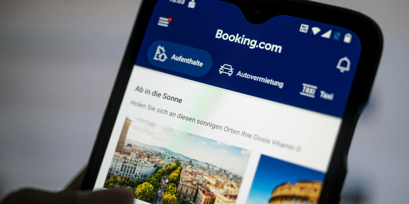 Eine Person scrollt sich auf dem Smartphone durch die App von Booking.com.