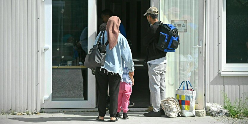 Eine Familie wartet vor einem Gebäude in einem Ankunftszentrum