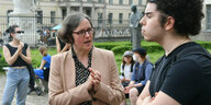 Uni-Präsidentin Julia von Blumenthal spricht mit einem jungen Mann, der seine Hände vor der Brust verschränkt