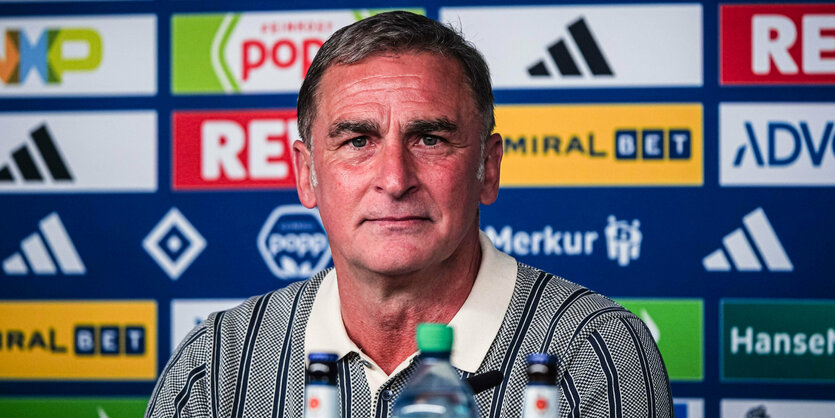 Stefan Kuntz sitzt auf dem Podium im Presseraum des HSV.