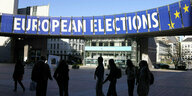 Eine Gruppe steht unter einem Wahlbanner vor dem Europäischen Parlament.