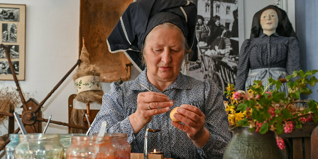 Eine Frau in traditioneller sorbischer Tracht bemalt Eier