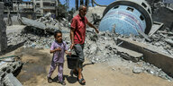 Menschen gehen neben einer zerstörten Moschee nach einem israelischen Luftangriff in der Stadt Deir al-Balah.