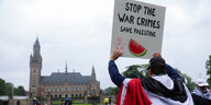 Ein Demonstrant hält vor dem Gebäude des IGH in Den Haag ein Schild hoch, auf dem steht: "Stop the War Crimes. Save Palestine"