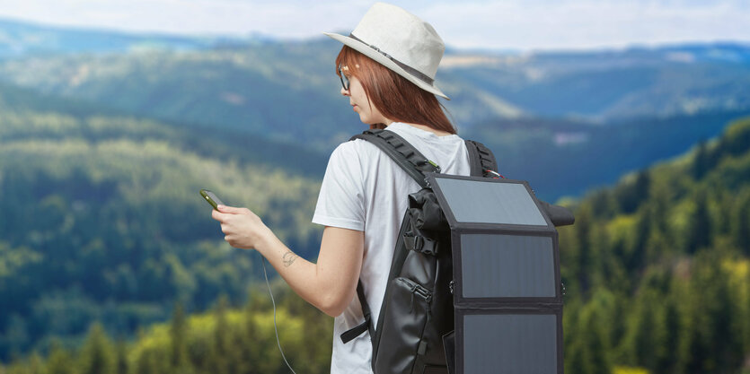 Wanderin vor Landschaft mit Rucksack mit Solarzellen