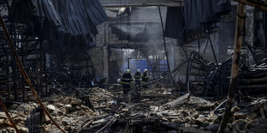 Feuerwehr-Kräfte gehen durch die Trümer einer von einem russischen Luftschlag völlig zerstörten Mall in Charkiw