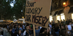 Your luxury, our misery steht auf einem Pappschild, das Demosntranten auf Mallorca hochhalten