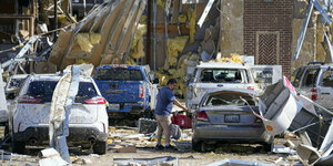 Ein Bewohner steht zwischen zerbeulten Autos und zerstörten Häuserfassaden