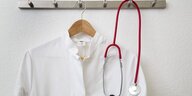 Arztkittel und Stetoskop hängen an einer Garderobe