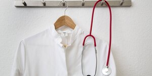 Arztkittel und Stetoskop hängen an einer Garderobe