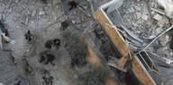 Aus der Vogelperspektive sind zerstörte Häuser zu sehen, Menschen laufen auf der Straße