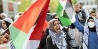 Frauen auf einer Demo tragen Hijab, Kufijas und Palästinafahnen