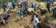 Menschen suchen nach einem Erdrutsch im Dorf Pogera nach Verschütteten.