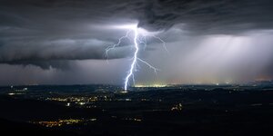 Blitze erhellen den Nachthimmel über einer Stadt