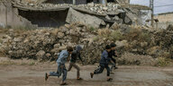 Kinder laufen an einem zerstörten Gebäude in Aleppo vorbei