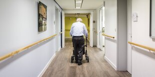 Ein Mann läuft mit seinem Rollator einen Gang entlang