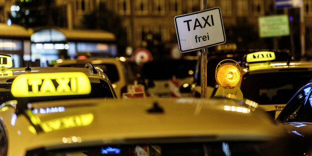 Vor einem Bahnhof stehen meherer Taxis - am beleuchteten Taxi-Schild auf dem Dach sieht man, dass viel frei sind