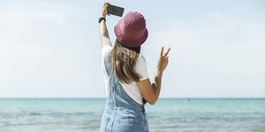 Eine Frau macht ein Selfie, sie trägt eine Latzhose