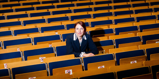 Eine Frau sitzt allein in einem Hörsaal. Es ist die TU-Präsidentin Geraldine Rauch