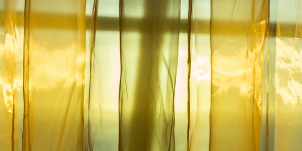 gelbes Sonnenlicht fältt diurch einen transparenten Vorhang