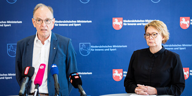 Landesbischof Ralf Meister und Innenministerin Daniela Behrens stehen nebeneinander hinter Tischen mit Mikrophonen.