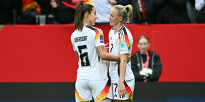 zwei Spielerinnen der DFB-Nationalmannschaft stehen auf dem Spielfeld und besprechen sich