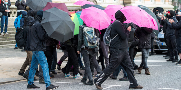 schwarz gekleidete Menschen mit bunten Regenschirmen vor dem Hamburger Landgericht
