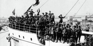 Winkende Männer mit Hüten an Deck eines Schiffs