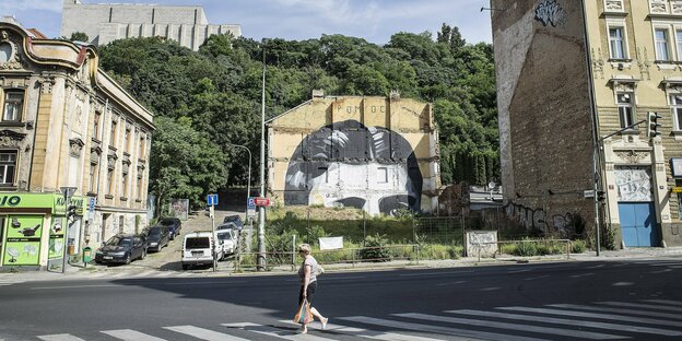 Straßenszene in Prag mit überlebensgroßem Kafka-Griffito an einer Häuserwand