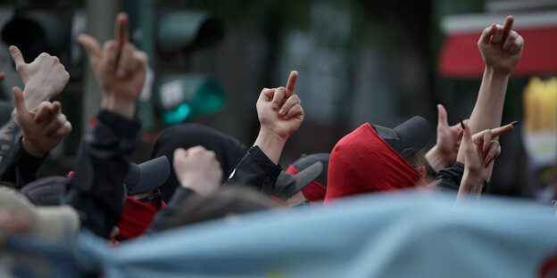 Teilnehmer der "Revolutionären 1. Mai-Demonstration" zeigen den Mittelfinger