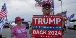 Ein Mann hält ein Plakat mit der Aufschrift "Trump Back 2024" in die Höhe